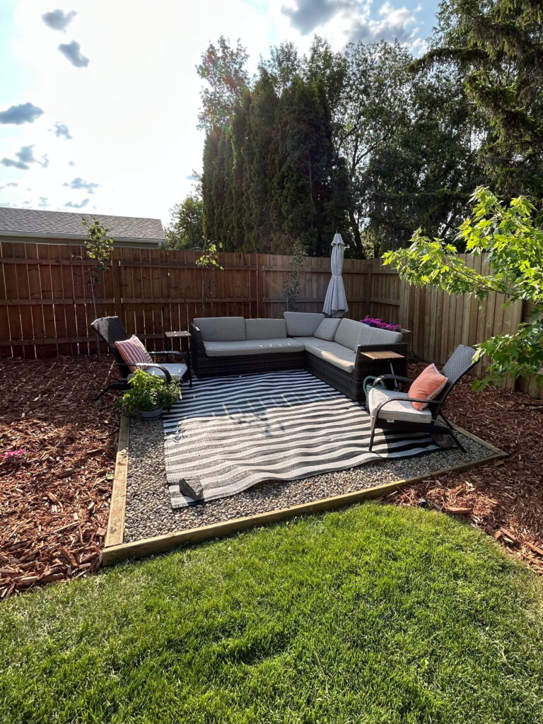Modern landscaping pad made of crushed rock and timbers. Fragrant cedar mulch surrounds the seating area with three Swedish Aspen trees and a silver maple providing shade and foliage.